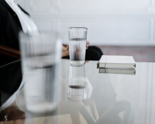 Glass of water on a desk next to a notebook